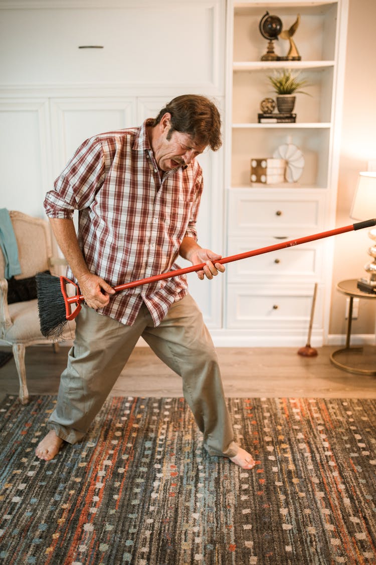 Man In Checkered Shirt Holding A Broom