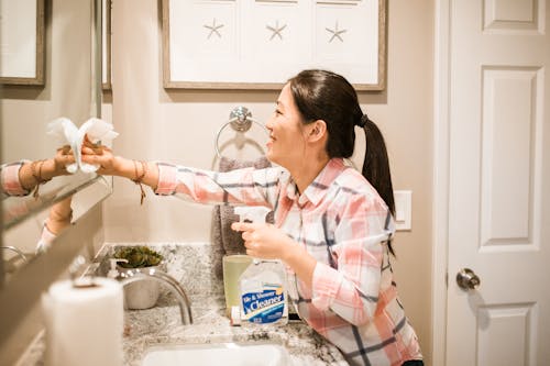 Woman Smiling While Cleaning the Mirror