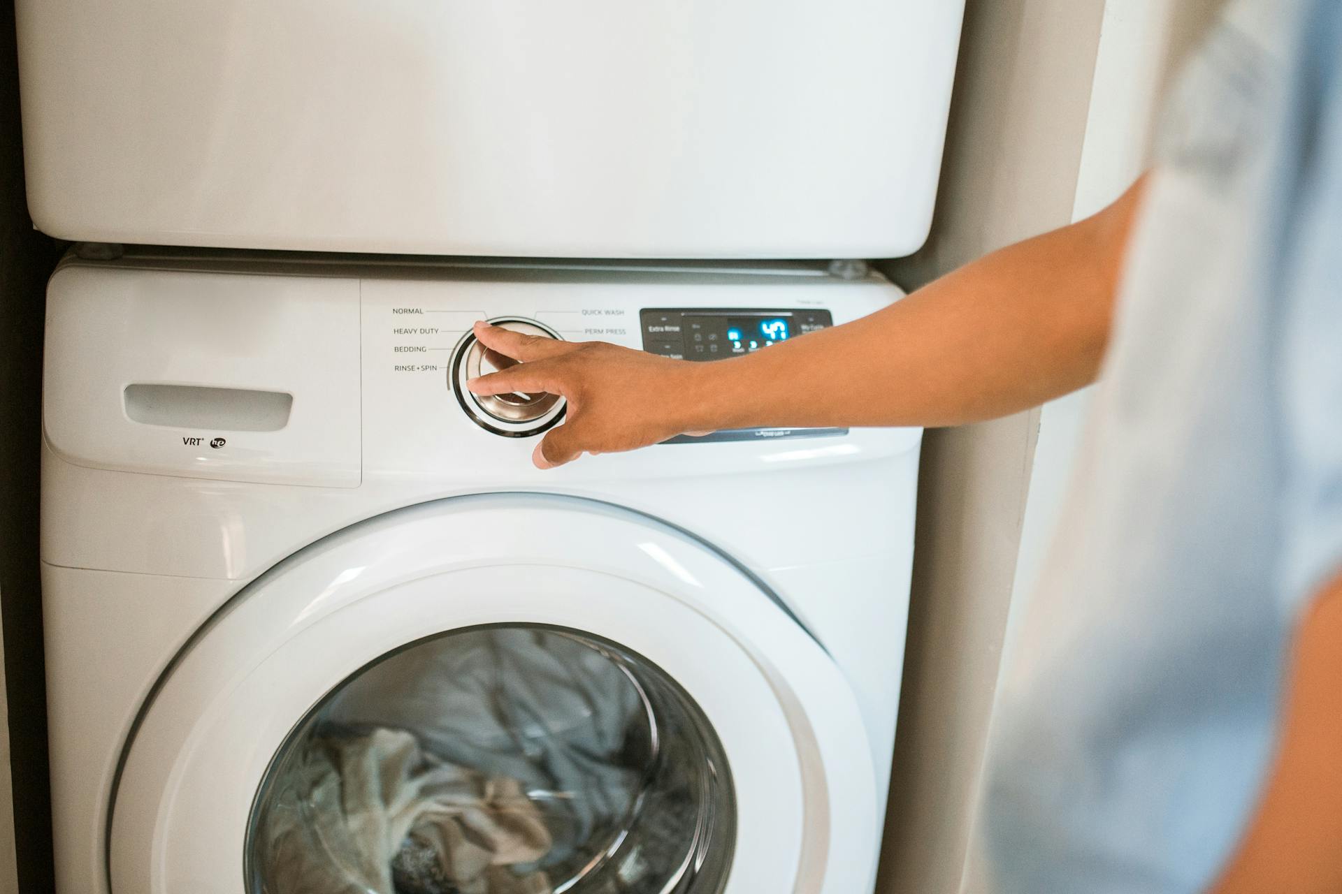 Close-up of a person adjusting a washing machine in a modern laundry room.