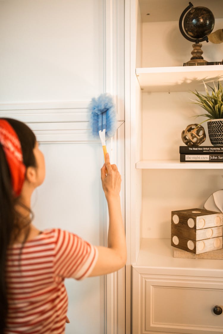 Woman Dusting Cabinets