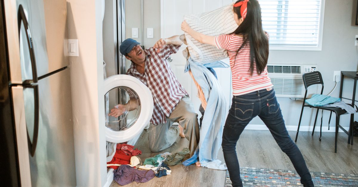 A playful couple doing laundry together, enjoying household chores.