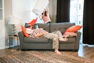 Woman in White and Black Stripe Shirt and Gray Pants Sitting on Gray Couch