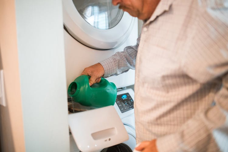 
A Man Pouring Detergent In A Washing Machine