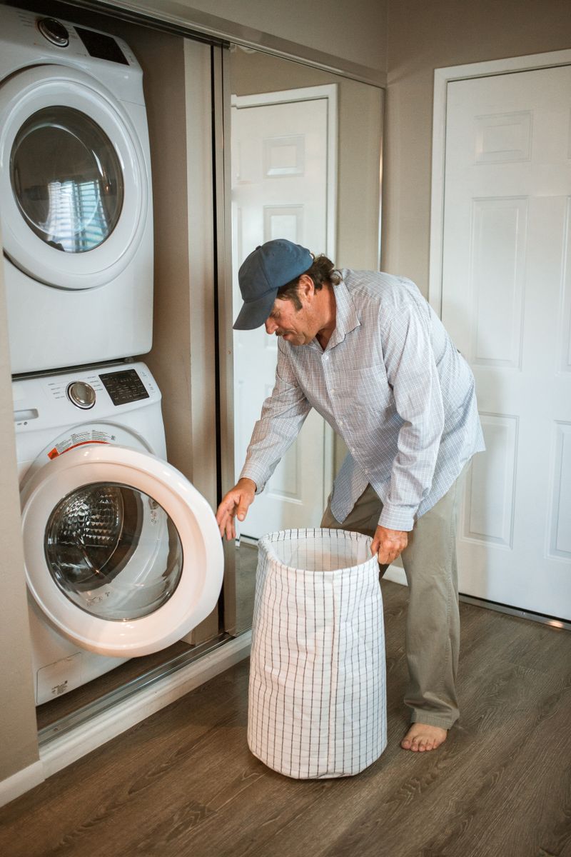 Man sorting fresh laundry beside a washing machine