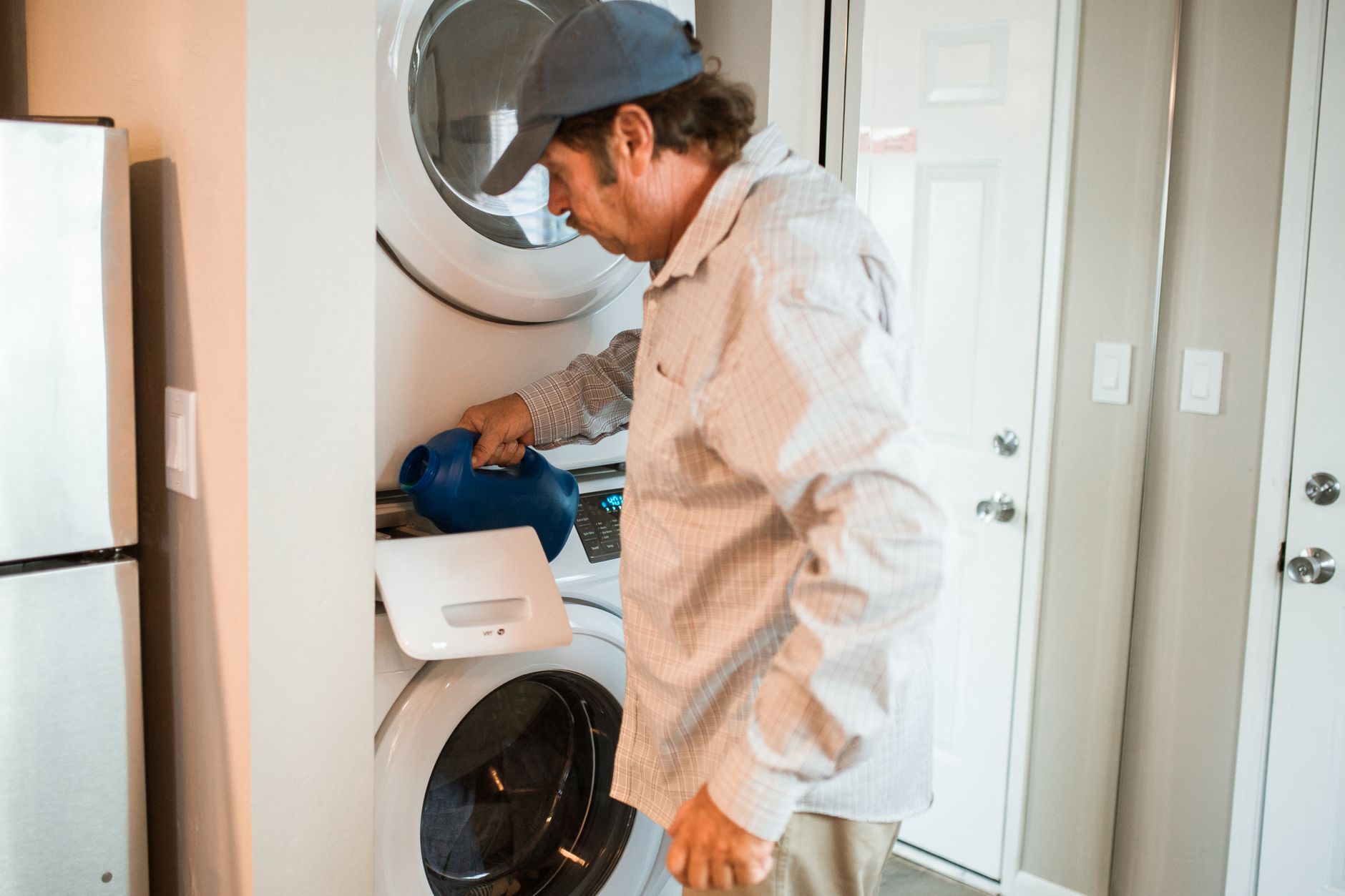 Person adjusting settings on a sleek washing machine in a modern laundry setting.