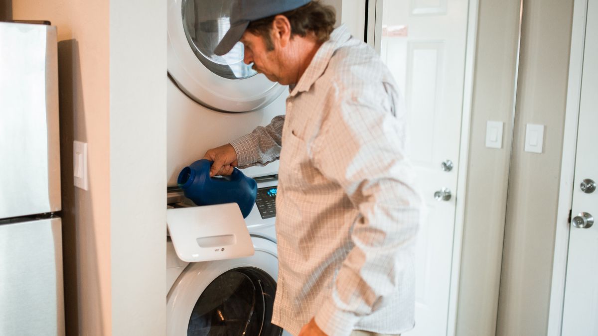 Loading detergent into a stacked washer and dryer.