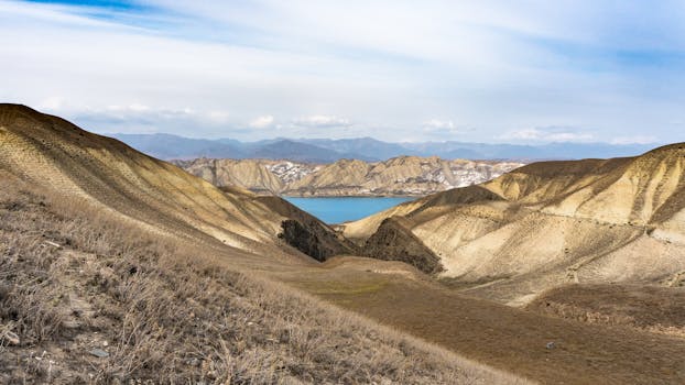 Breathtaking view of arid hills and a serene lake in Talas Region, Kyrgyzstan.