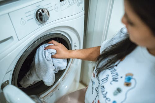 Vrouw In Grijs Shirt Staande Voor Witte Voorlader Wasmachine