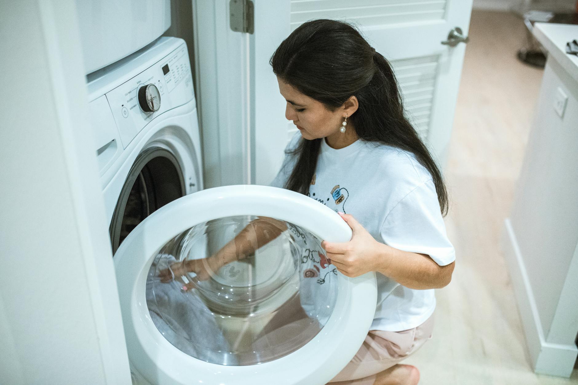 a lady adding clothes in washing machine