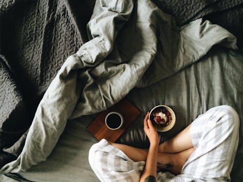 Crop woman with breakfast in bed