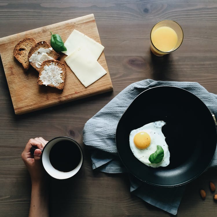 Free Crop person sitting at table with homemade breakfast Stock Photo