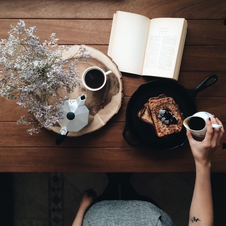 Crop woman with dessert and book