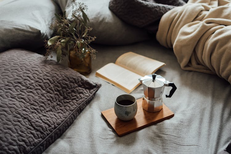 Coffee And Book On Comfortable Bed