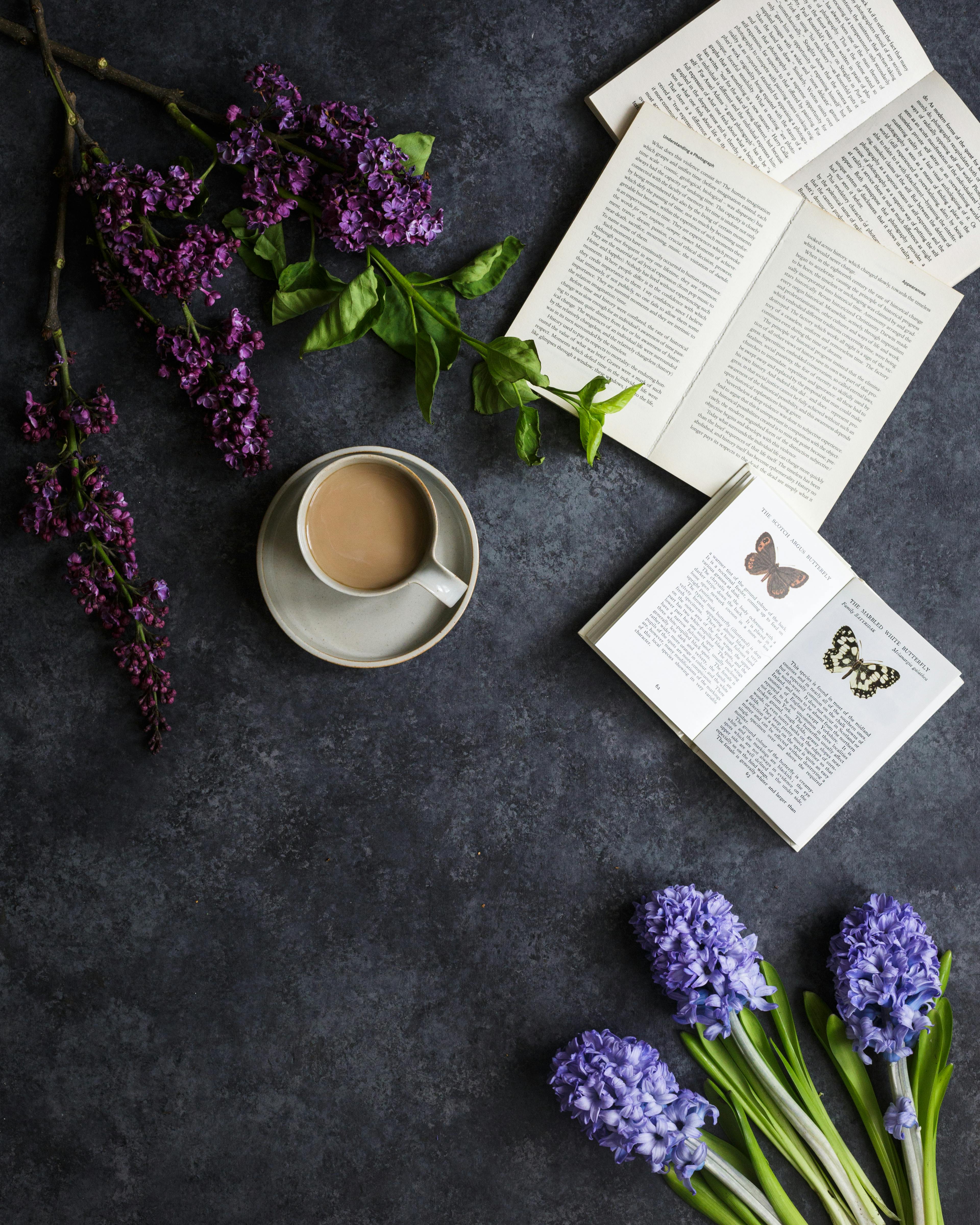 cup of coffee near flowers and book