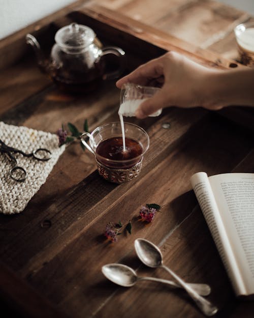Free Crop person preparing coffee and reading Stock Photo