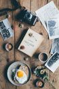 Top view of fresh coffee and tasty meal near retro camera and old pictures on wooden table