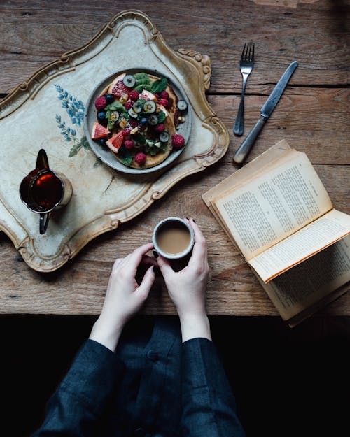 Free Crop woman with book and breakfast Stock Photo