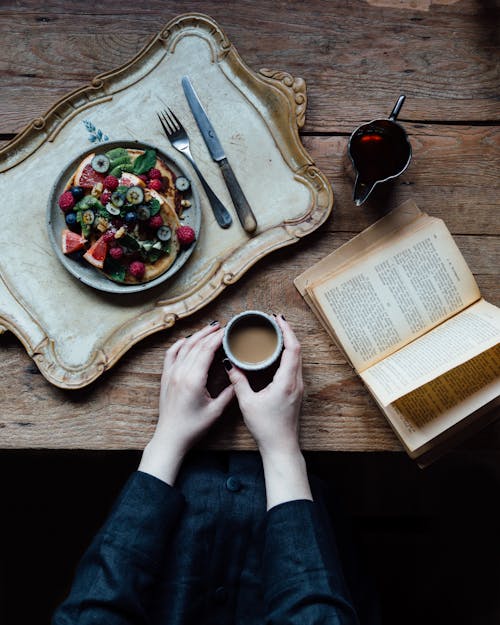 Free Crop woman having breakfast and reading Stock Photo