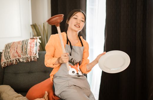 Homeowner holding a plunger, ready for a clogged toilet