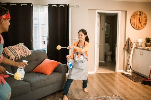 Free A cheerful couple engages in a playful cleaning session in their home. Stock Photo