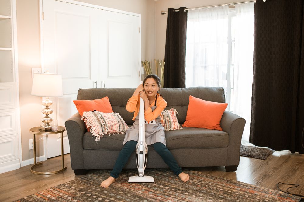 Cleaner seated with a vacuum in a welcoming living room