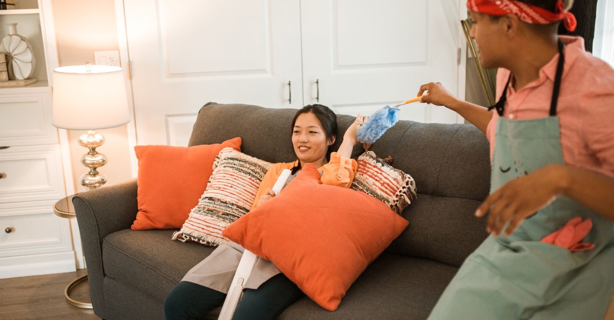 A cheerful couple having fun while playfully cleaning their living room together.