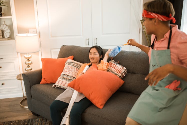 Smiling Couple Sitting On Couch And Cleaning Room