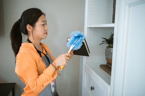 Woman in Yellow Polo Shirt Holding Blue Feather