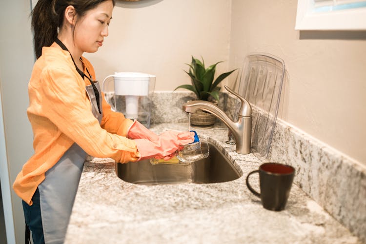 Woman Wearing Pink Gloves Washing A Drinking Glass 