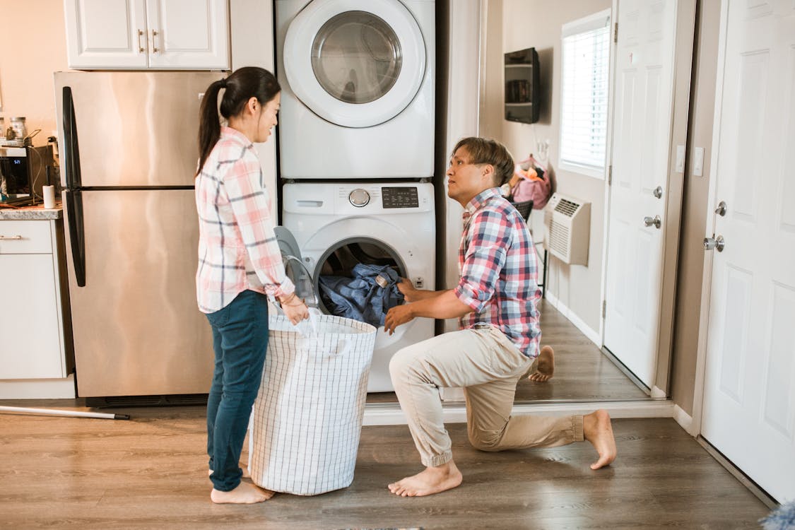 Man in White and Red Plaid Dress Shirt and White Pants Standing Beside White Front Load