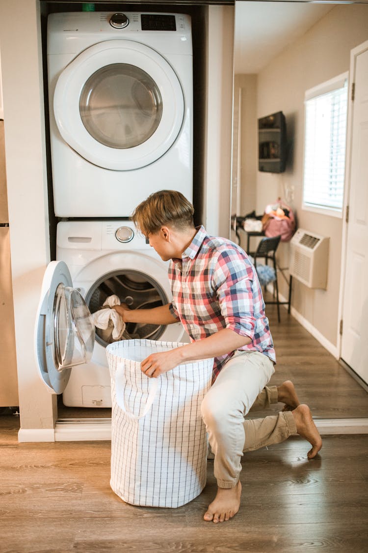 A Man Putting Clothes On The Laundry Machine