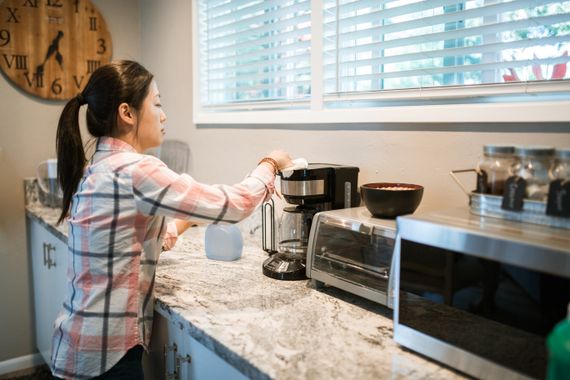 Woman carefully wiping a coffee maker in a bright modern kitchen