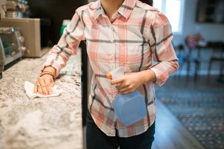 A Woman Wiping A Kitchen Counter