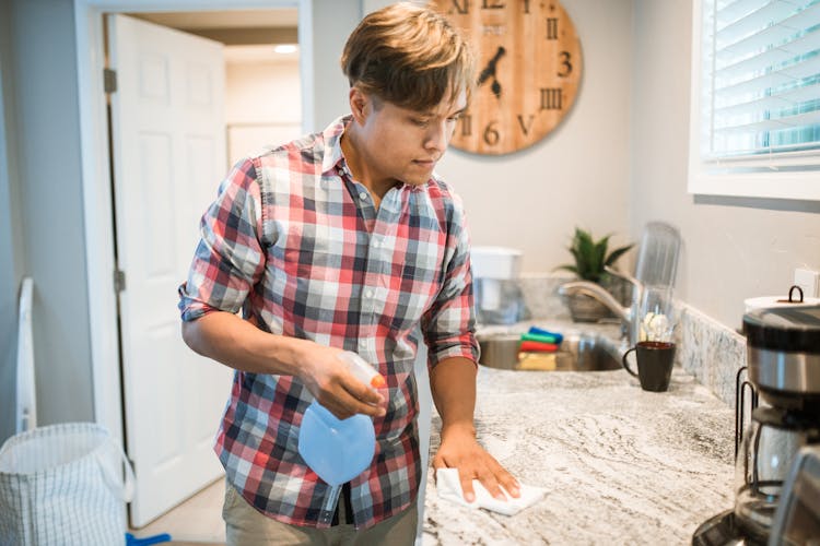 A Man Wiping A Kitchen Counter