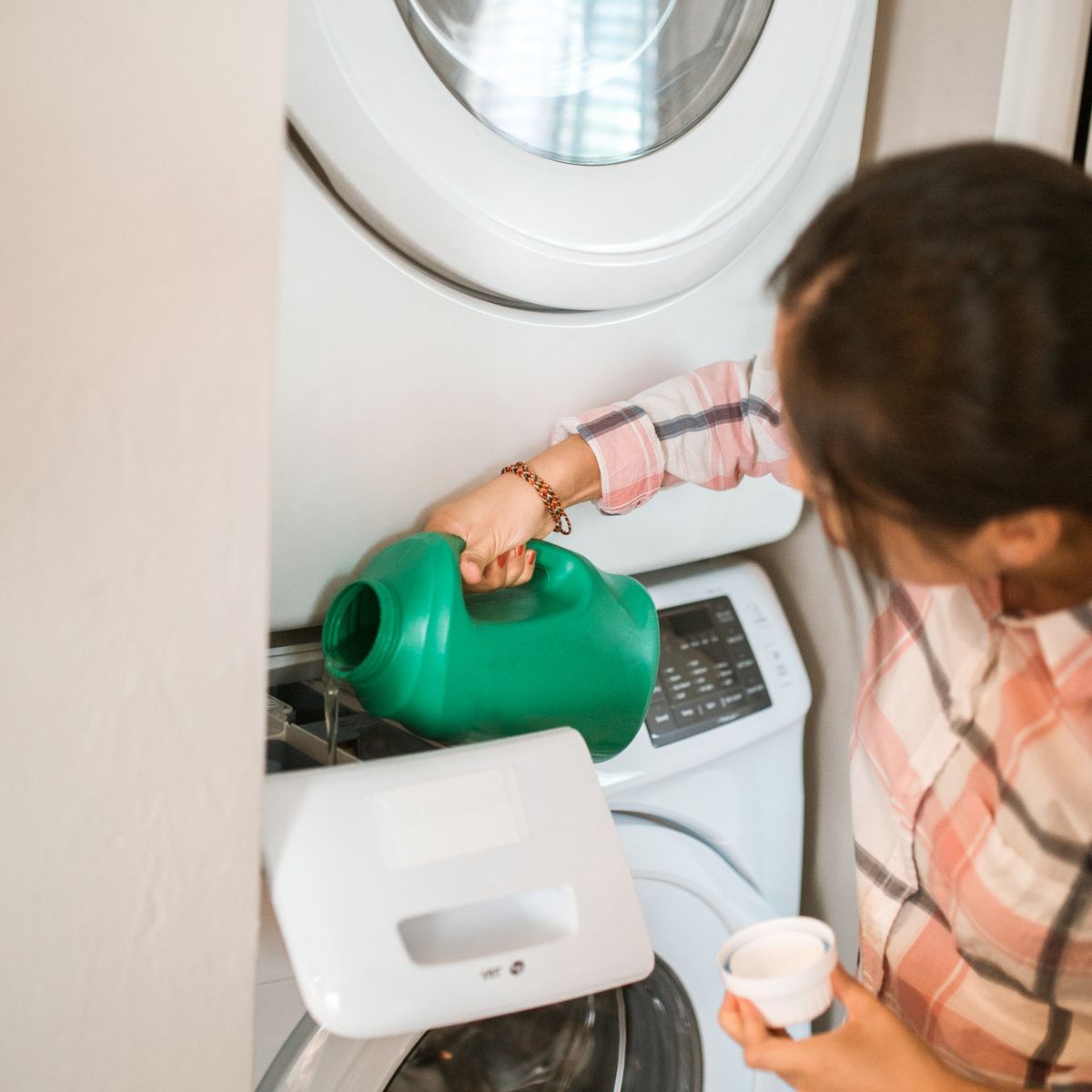 Pessoa colocando produto na gaveta de uma máquina de lavar