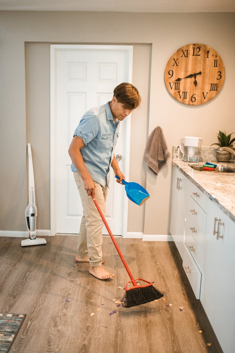 Photo Of A Man In A Blue Shirt Sweeping The Floor