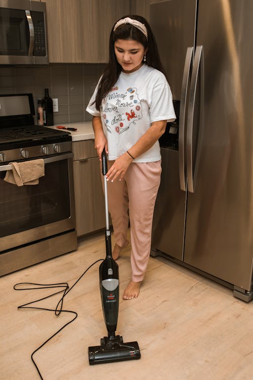 Woman in White T-shirt and Beige Pants Standing Beside Silver Bottom Mount Refrigerator