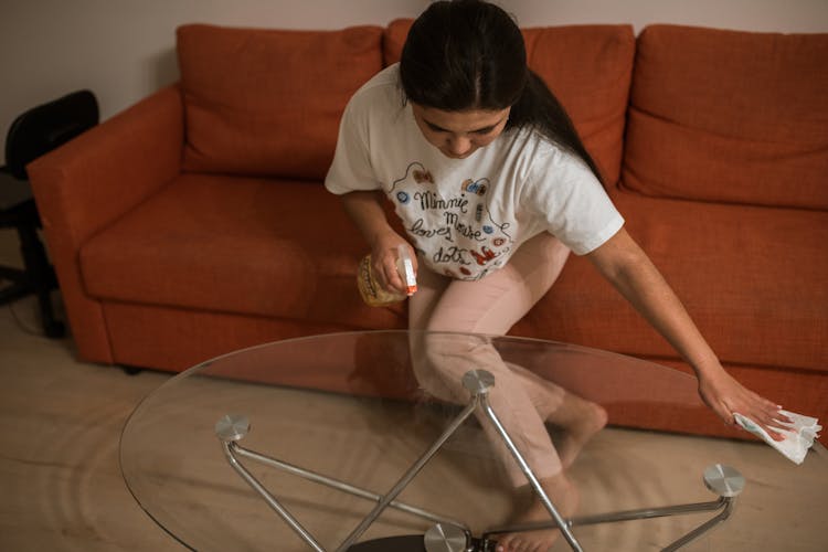 A Woman Cleaning A Glass Center Table