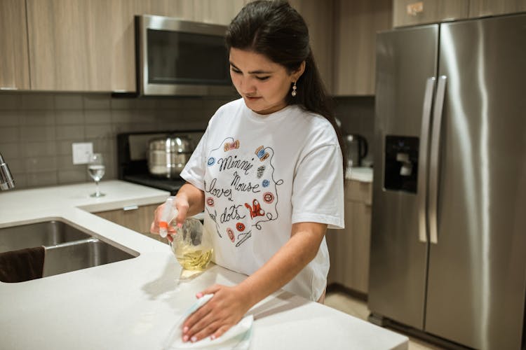 A Woman Wiping A Kitchen Counter