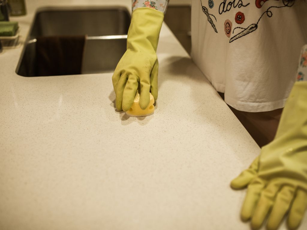 Cleaner spraying and wiping a kitchen surface