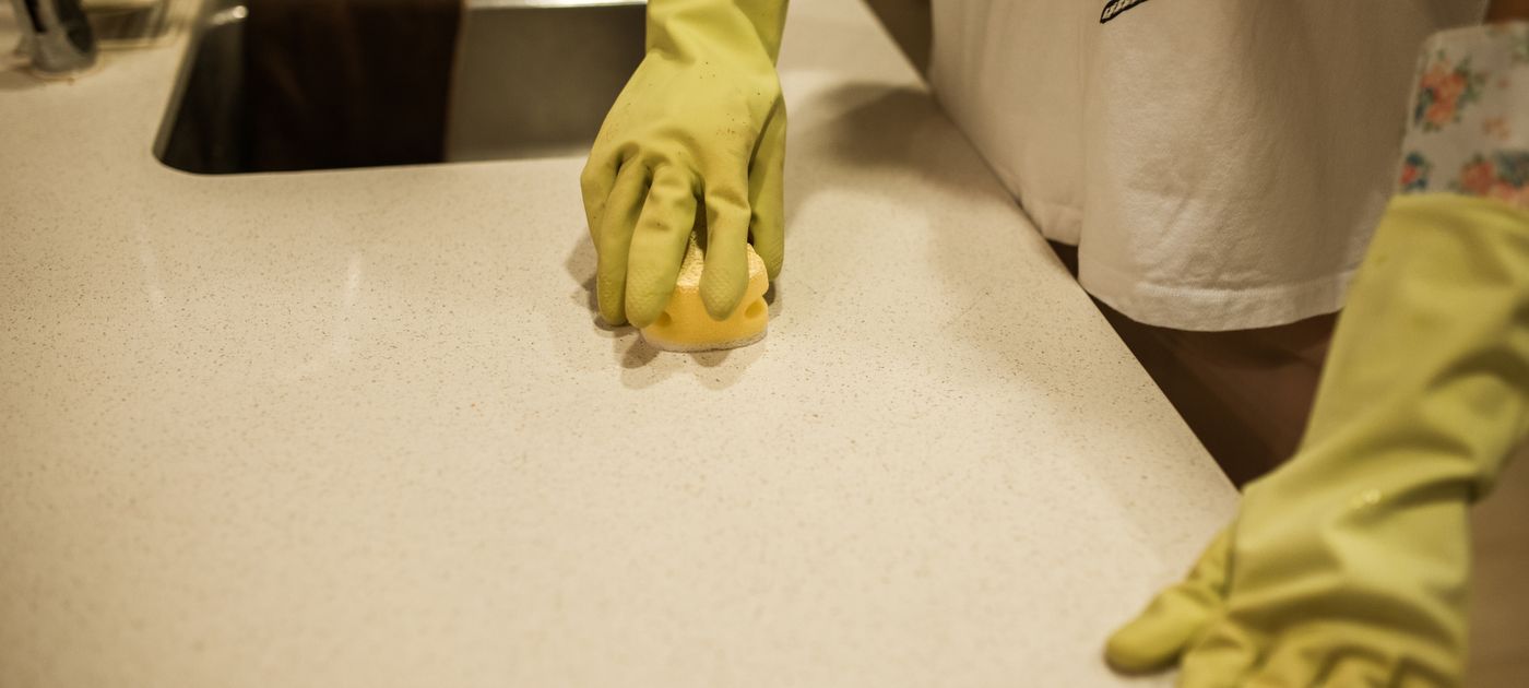 A person wiping down a kitchen counter while preparing the home for a pest control visit