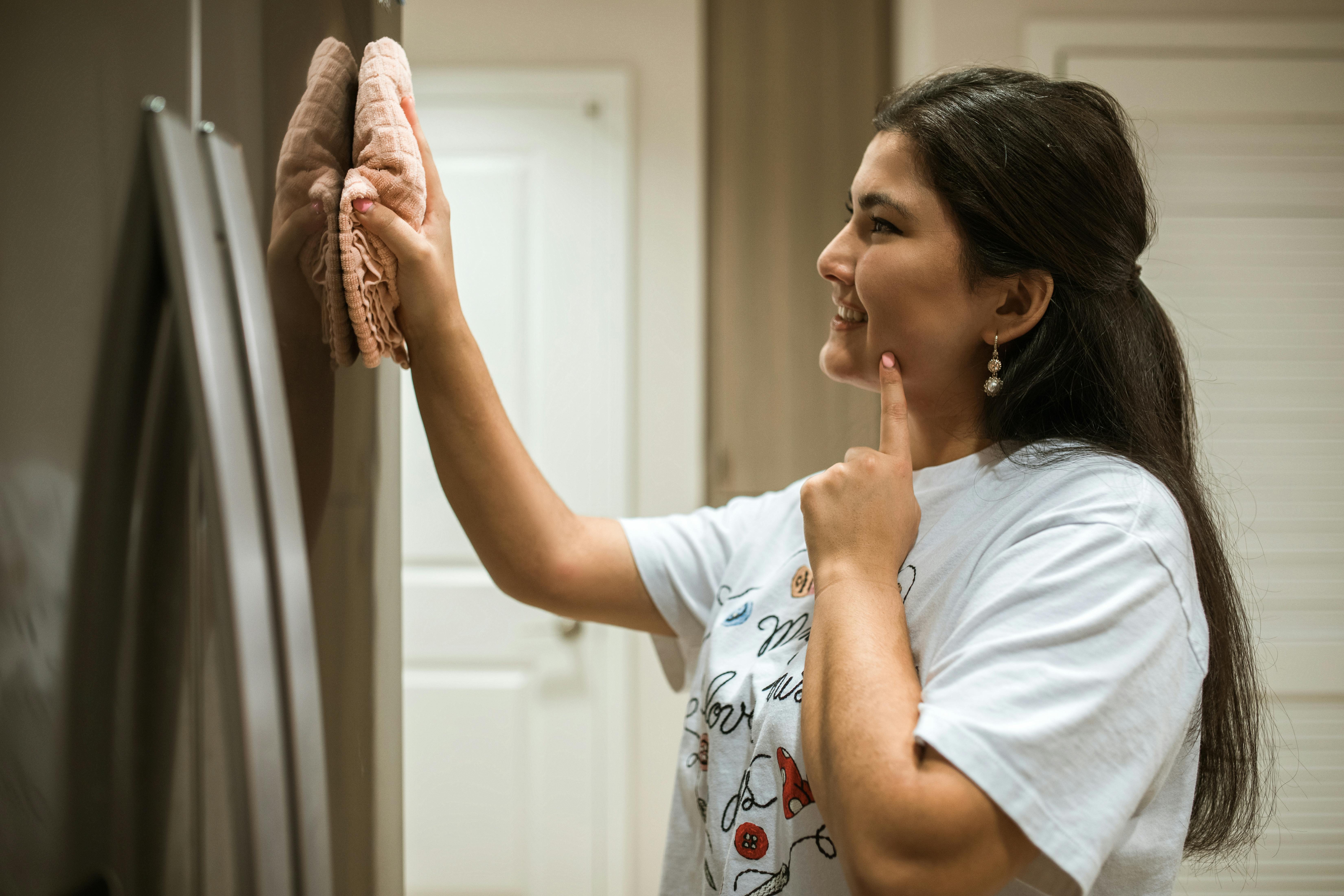 a woman wiping a refrigerator with a cloth