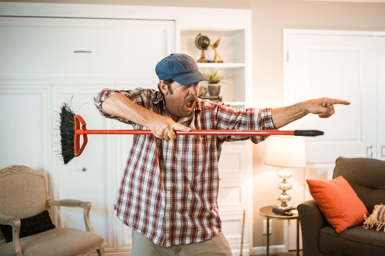 Man In Plaid Shirt Holding A Broom Stick