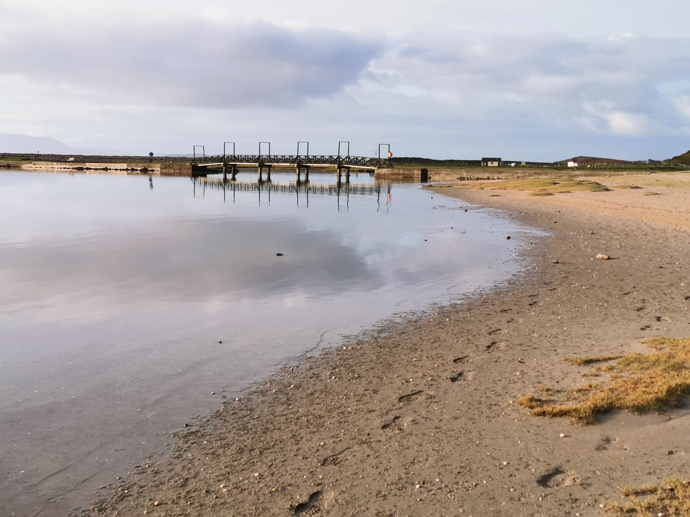 Peaceful beach view with pier and reflections in County Mayo, Ireland