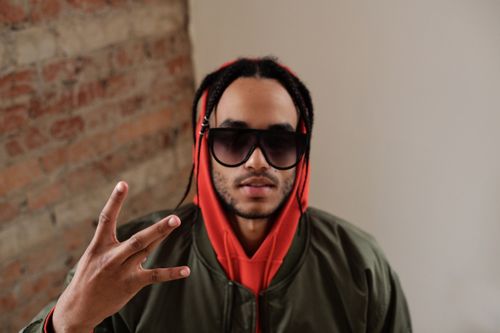 Free Portrait of a stylish young man with dreadlocks and sunglasses posing indoors. Stock Photo