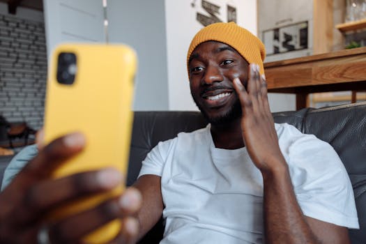 A cheerful man in a beanie making a video call on his smartphone indoors.