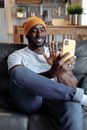 Man in White Crew Neck T-shirt and Blue Denim Jeans Sitting on Black Sofa