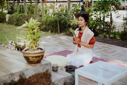 Woman Holding a Plant while Praying