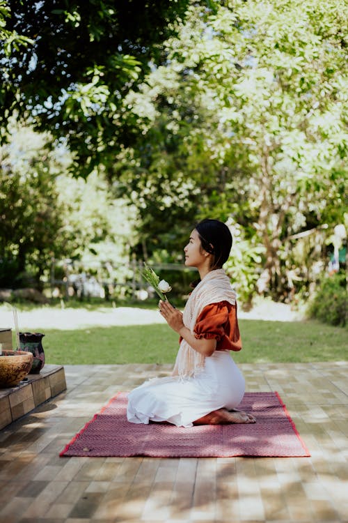 A Woman Kneeling on a Mat while Praying