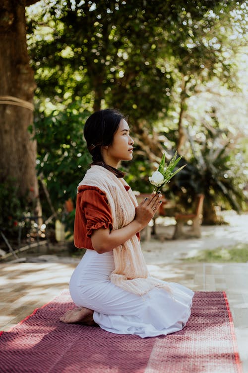 A Woman with a White Flower Praying while Kneeling